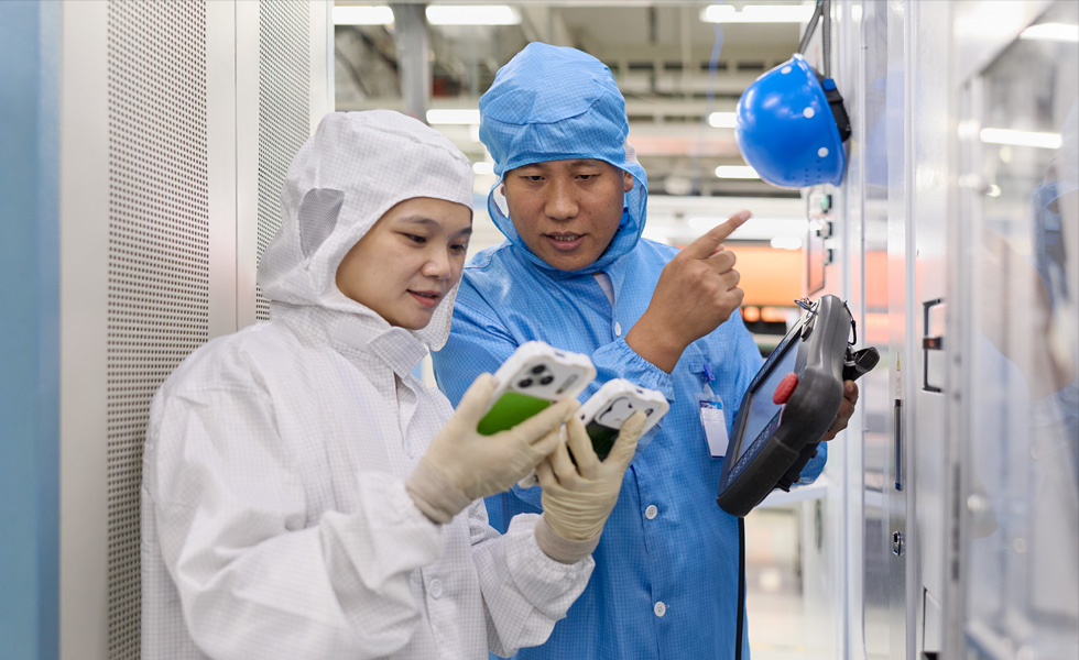 两个身着连体工作服的人正在使用两部 iPhone 设备开展协作